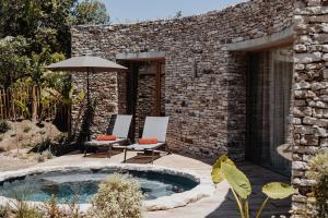 博尼法乔A SPERANZA Suites de Charme by A Cheda的庭院设有热水浴池、2把椅子和遮阳伞。