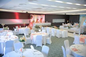 基加利Ubumwe Grande Hotel的宴会厅配有白色的桌子和白色的椅子