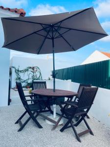 奥比多斯Casa do Canto - Uma casa no campo, perto da praia.的一张桌子和两把椅子及雨伞