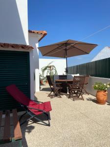 奥比多斯Casa do Canto - Uma casa no campo, perto da praia.的庭院配有桌椅和遮阳伞。