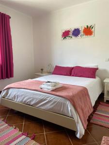 奥比多斯Casa do Canto - Uma casa no campo, perto da praia.的一间卧室配有一张大床,提供红色和紫色枕头