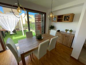 圣乌尔苏拉Tenerife Family Home的一间带木桌和白色椅子的用餐室