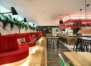 伦敦citizenM London Victoria Station的一间设有红色座位的餐厅和一间酒吧