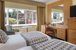 埃文河畔斯特拉特福The Welcombe Golf & Spa Hotel的配有一张床和一张书桌的酒店客房