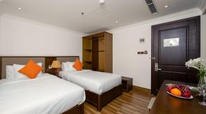 岘港Roliva Hotel & Apartment Danang的酒店客房设有两张床,桌子上放着一碗水果