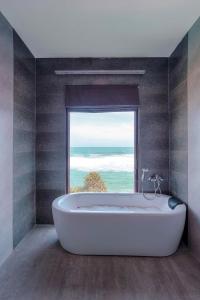 米瑞莎Beach & Bliss Mirissa的带浴缸的浴室和大窗户