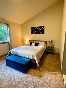 阿什福德NEW Modern Cabin! 5mi to Mt Rainier National Park! Hot Tub & Wifi的一间卧室配有一张大床和蓝色的搁脚凳