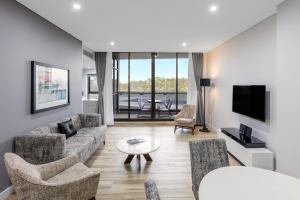 悉尼帕拉马塔教堂街美利通公寓式酒店的客厅配有沙发、椅子和电视