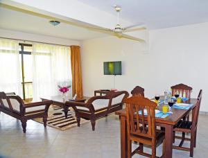迪亚尼海滩Galu Gardens Apartments Diani Beach的客厅设有餐桌和椅子