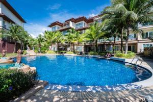 邦涛海滩Hotel COCO Phuket Bangtao - SHA Extra Plus的棕榈树建筑前的游泳池