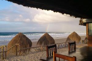 伊尼扬巴内Casa Coco Palmeira的海滩上一群带彩虹的草屋