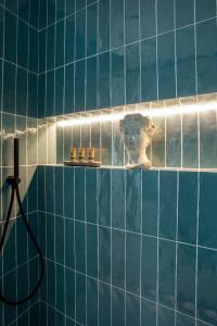 巴勒莫Vossia Luxury Rooms & Sicilian Living的蓝色瓷砖浴室,在架子上设有头雕像