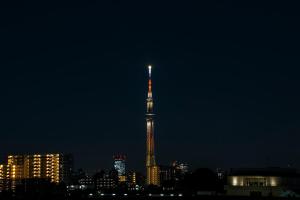 东京Minn Machiya的一座高大的建筑,晚上有旗帜