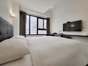 台中市雀客快捷台中福星的白色卧室设有一张大床和一台平面电视。