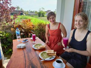 艾湄湾Agung Inn Amed的两个坐在桌子边的女人,拿着食物和饮料