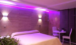 马德里游侠酒店的一间设有一张床铺和一张紫色灯桌的房间