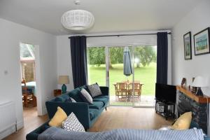 拉斯姆兰Idyllic 3-Bed House minutes from village & beach的客厅设有蓝色的沙发和滑动玻璃门