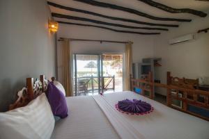 南威坦桑石海滩度假村酒店的一间卧室配有一张白色大床,上面有紫色花朵