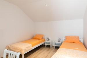 杜布罗夫尼克Apartments Katarina的配有白色墙壁和木地板的客房内的两张床