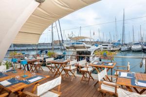 热那亚Locanda da Toto的码头上带桌椅和船只的甲板