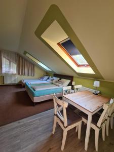 米什科尔茨Palantír Panzió的一间卧室配有一张床、一张桌子、一张床和一个窗户。