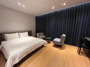 昌原市Jinhae Intercity Hotel的卧室配有一张床和一张桌子及椅子