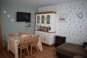 巴利纳Cosy two bedroom cottage on the Mullet Peninsula的一间带桌椅和电视的用餐室