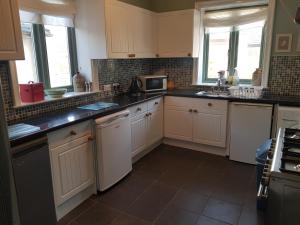 锡斯凯尔Ideally located Cumbrian home with stunning views的厨房配有白色橱柜和黑色台面