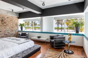 迈阿密海滩鹈鹕酒店的一间卧室配有一张床和两把椅子,还有两个窗户