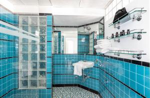 迈阿密海滩鹈鹕酒店的蓝色瓷砖浴室设有水槽和淋浴