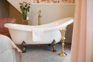米科瓦伊基La Rose Residence的浴室里设有白色浴缸,花瓶装有花卉