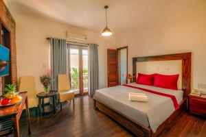 会安Calm House Hotel Hoi An 1的一间卧室配有一张带红色枕头的床和一张桌子