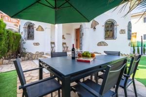 迈阿密普拉特亚Charming Mediterranean house with private jacuzzi sea and mountain views的一张带椅子的黑桌和一把绿色雨伞