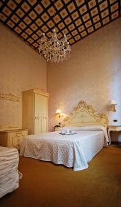 威尼斯都灵诺酒店的卧室配有一张带吊灯的大型白色床。