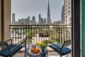迪拜Durrani Homes - Modern Living at Burj Views的阳台配有两把椅子和一张带一盘食物的桌子。