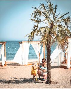 凯麦尔premium park apart otel的坐在海滩上棕榈树下的女人和孩子
