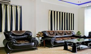 瓦拉纳西Itsy By Treebo - Ashoka Grand的客厅配有2把皮椅和沙发