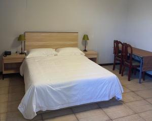 路易港Kirin Guesthouse and Restaurant的卧室配有白色的床和桌椅