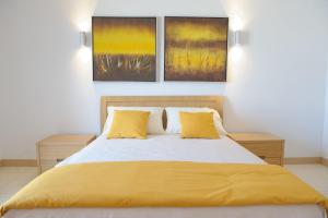 圣玛丽亚Agua Hotels Sal Vila Verde的一间卧室配有一张带黄床单和两幅画作的床。