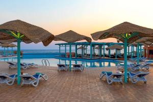 库塞尔库塞尔丽笙度假酒店的一个带遮阳伞和躺椅的游泳池以及一个游泳池