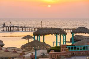 库塞尔库塞尔丽笙度假酒店的日落时分带遮阳伞和码头的海滩