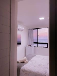 纳塔尔Acomodação aconchegante à beira- mar的白色的卧室设有床和窗户
