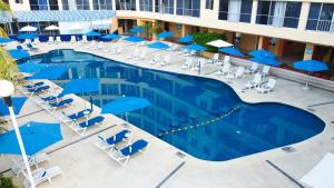 阿卡普尔科Ritz Acapulco All Inclusive的享有带椅子和蓝伞的游泳池的上方景色
