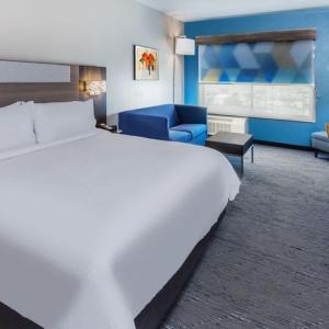 罗森伯格Holiday Inn Express & Suites - Houston SW - Rosenberg, an IHG Hotel的卧室配有一张白色大床和一张蓝色沙发。