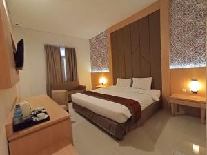 梭罗Al Azhar Azhima Hotel Resort and Convention的酒店客房带一张大床和一把椅子
