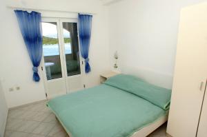 赞吉纳Apartments by the sea Luka Dubrava, Peljesac - 4568的一间卧室配有一张带蓝色窗帘的床和一扇窗户