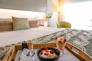 布里斯班The Point Brisbane Hotel的床上的托盘,上面放着一碗谷物和水果