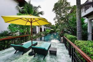 查龙Coco Retreat Phuket Resort and Spa - SHA Plus的一个带黄色遮阳伞和椅子的庭院和一个游泳池