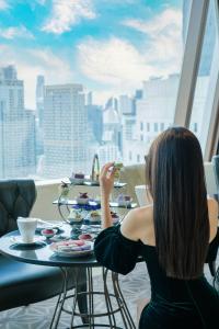 曼谷曼谷大倉新頤酒店的坐在窗前桌子上的女人