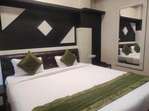 古瓦哈提Hotel Rudraksh- Near VIP Airport Guwahati的卧室配有带绿色枕头的大型白色床
